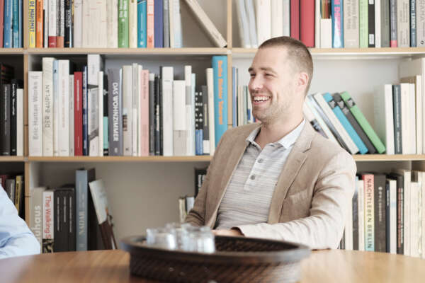 Ein MVB-Mitarbeiter sitzt an einem Tisch vor einem Bücherregal.